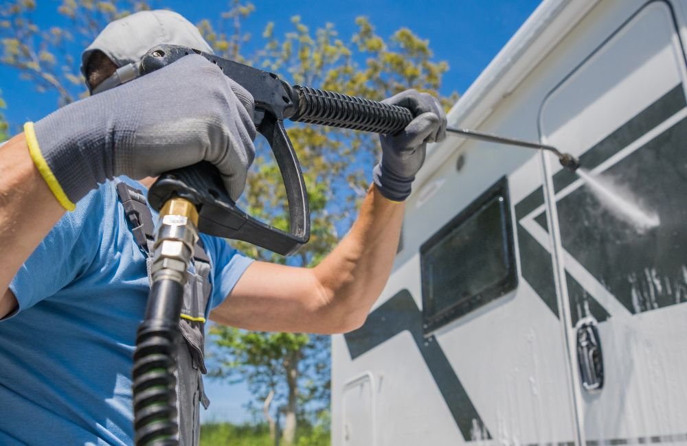 An image of a person using a power washer to clean a vehicle.