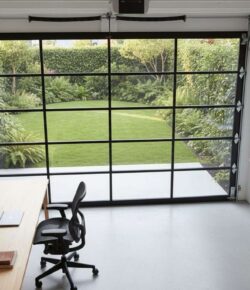 A modern garage-to-office conversion featuring a clear glass garage door.