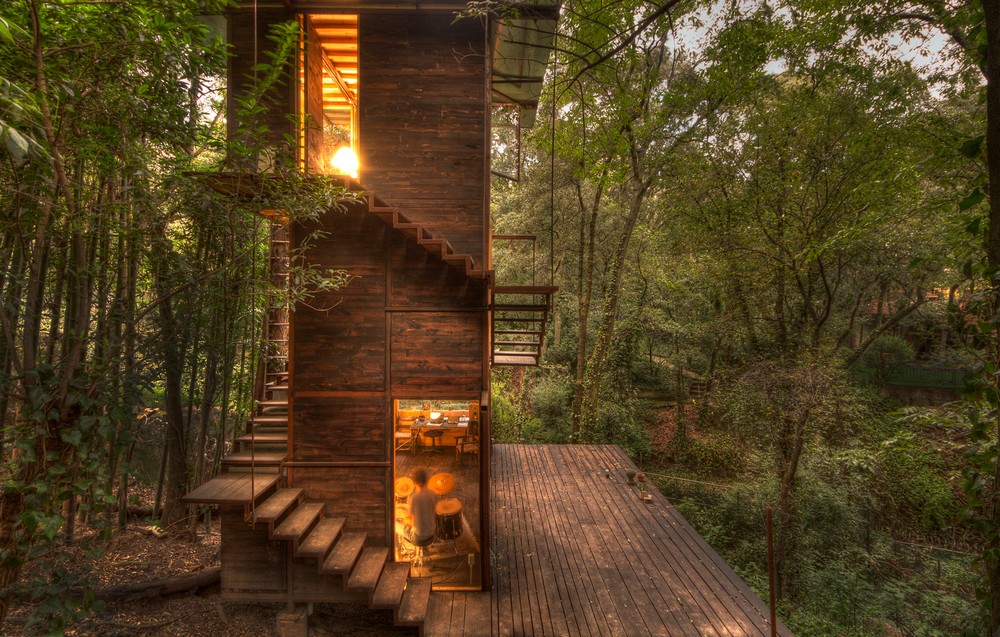 The fully illuminated Casa Flotante looks like a beacon in the midst of the forest.