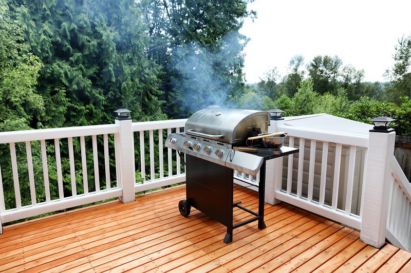 An image of a gas grill on a wood patio. 