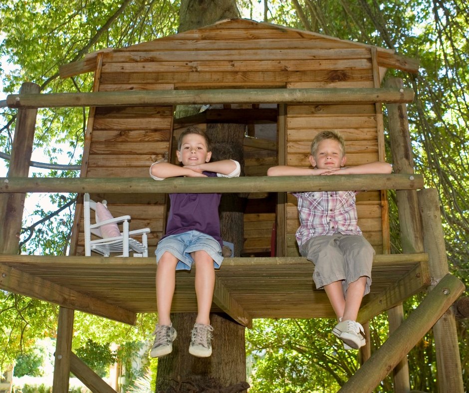 2 young boys sitting quietly on a tree house