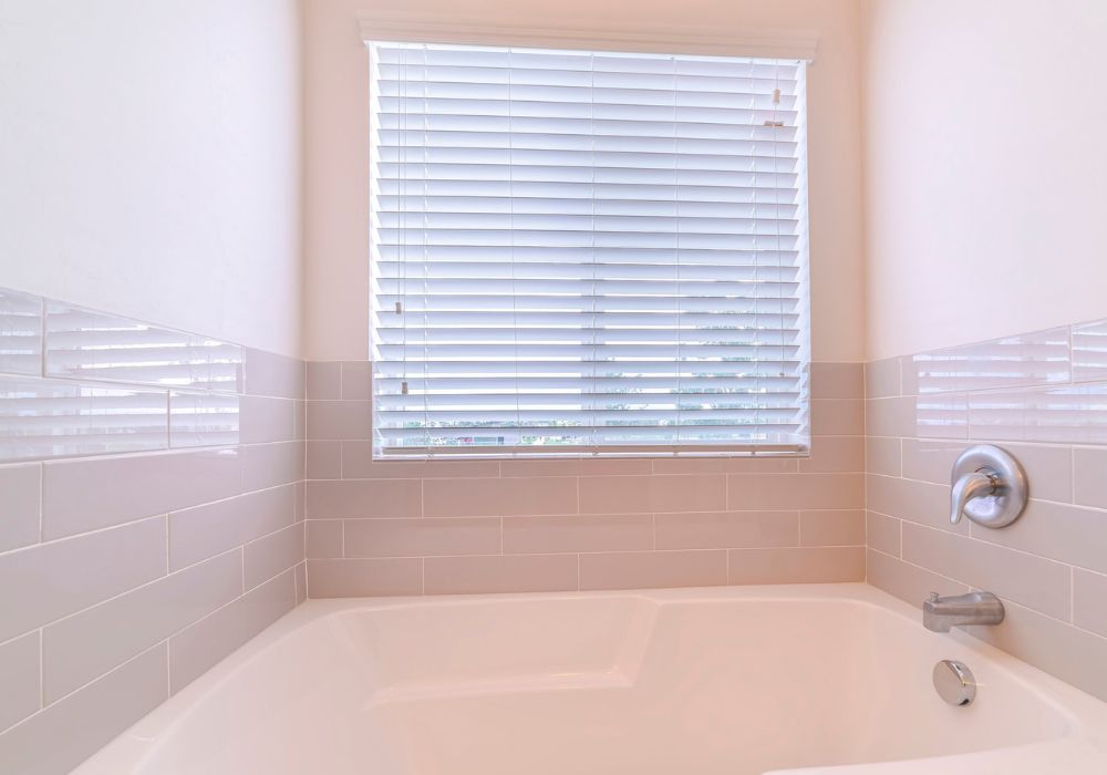 An image of a curtain letting in natural light to a small bathroom. 