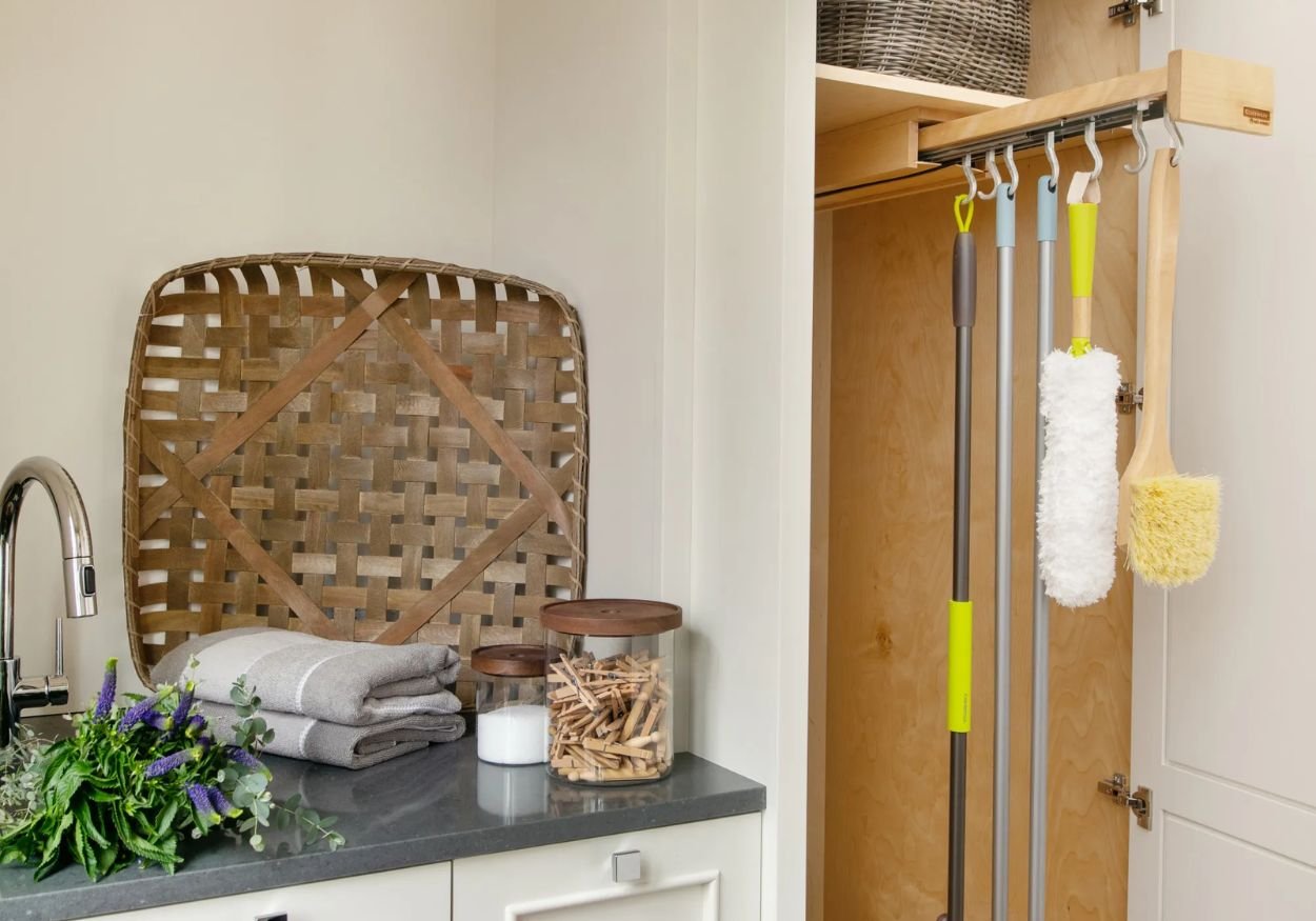 An image of the Glideware pull-out cabinet organizer holding brooms. 