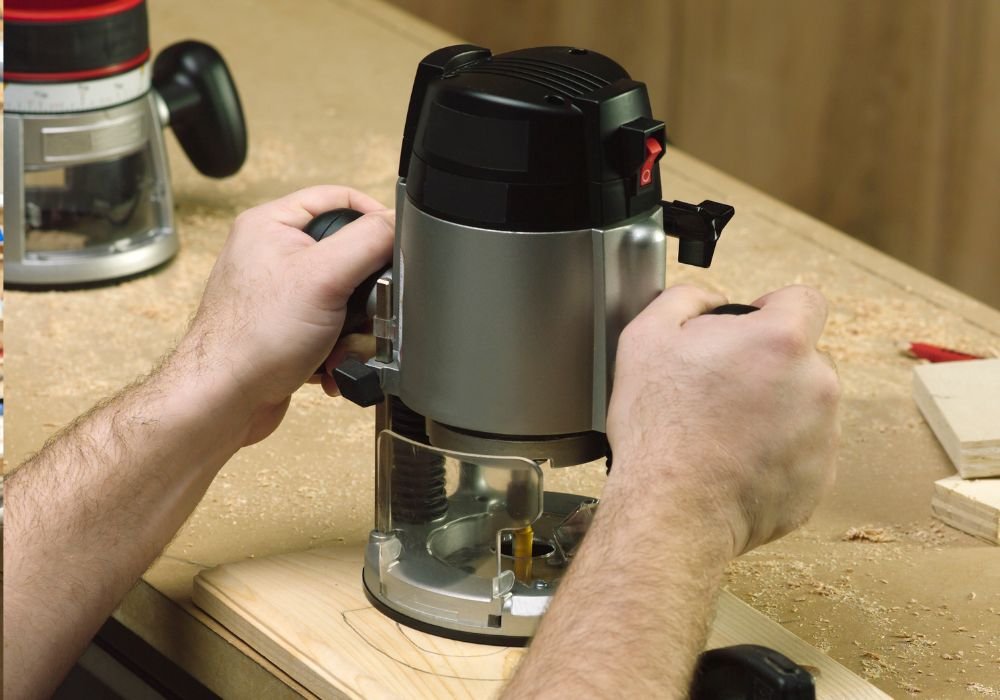 An image of a man working on a handheld wood router. 