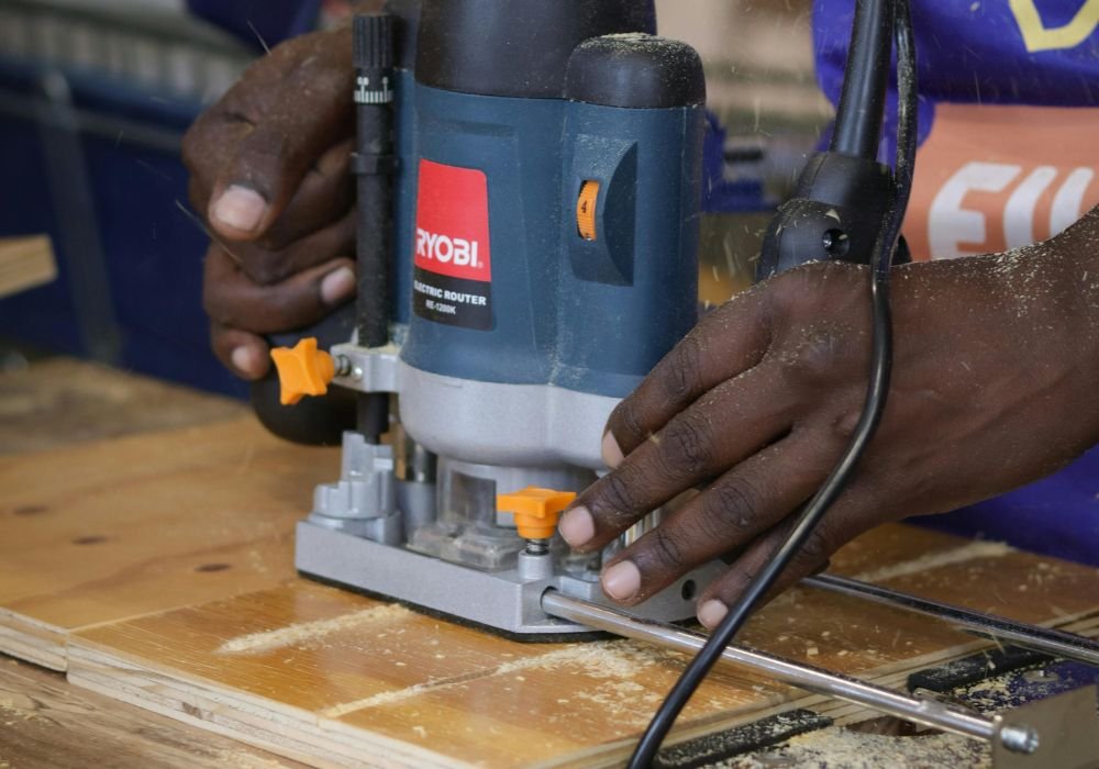 An image of  DIY'er using an edge guide with their wood router. 