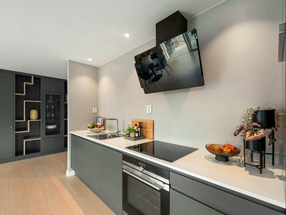 An image of a one-wall kitchen layout with a wall-bracketed TV. 