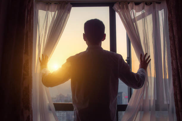 a man is looking at the sunset through the new European tilt and turn window