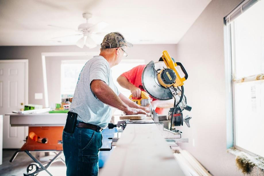 An image of two people working on a wood piece.